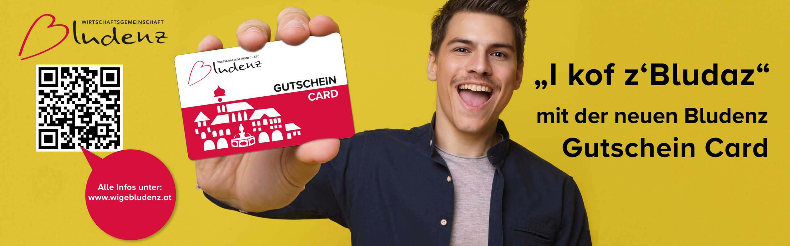 Impressed handsome young person holds in hand debit credit card happy open mouth isolated on yellow color background. Close up of big bank card in hand of 20s young man hipster in blue shirt